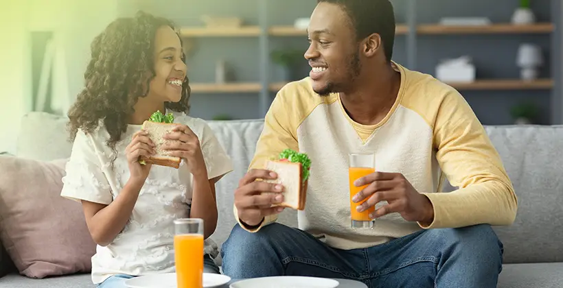 Father eating a snack with his daughter, smiling together