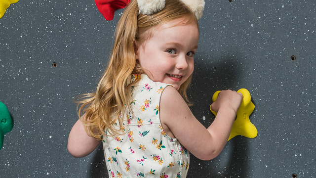 Infant in indoor climbing wall facing viewer