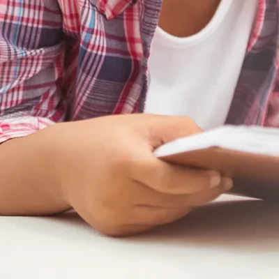 Cropped view of a child reading a book while laying down