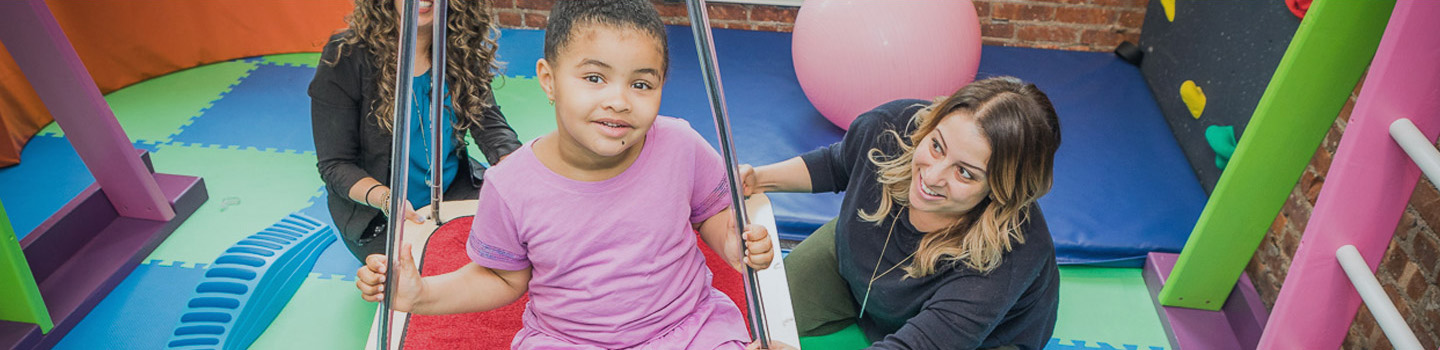 Two therapists interacting with an infant on a swing