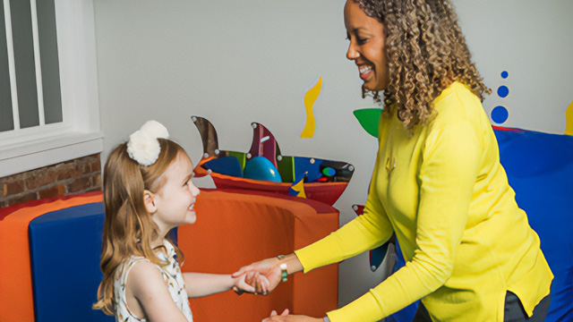 Therapist holding hands with a smiling child