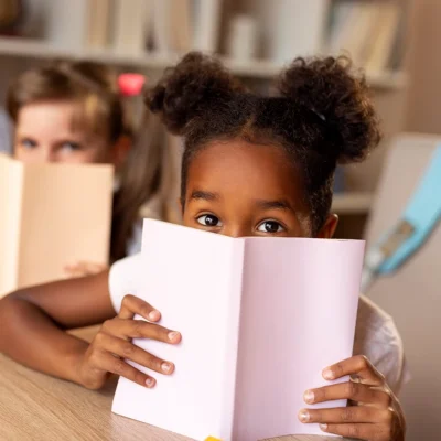 Children hiding behind books playfully.