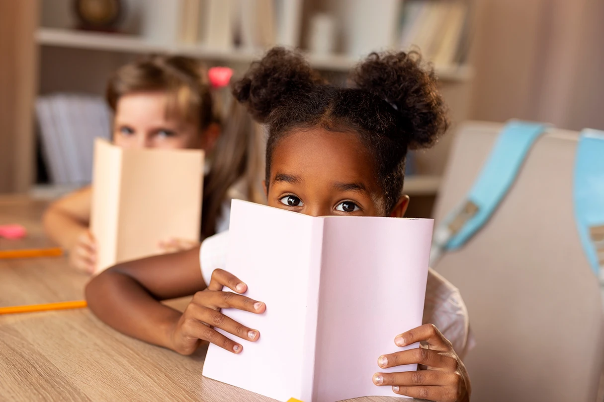 Children hiding behind books playfully.